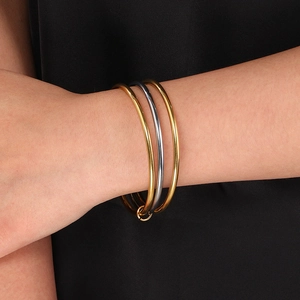 Close-up of three interlocking 3mm stainless steel bangles in mixed gold and silver tones