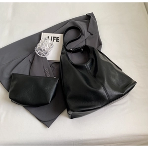 Flat lay of black PU leather tote bag with matching pouch and casual office accessories
