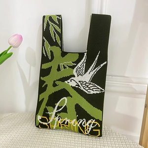 Detail of green knitted knot bag with white swallow motif and Spring text design