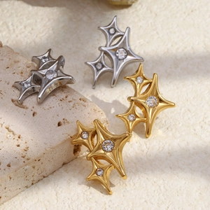 Macro detail of 18K gold plated four-pointed star studs with zircon on beige stone texture