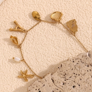 Detailed shot of 18K gold plated ocean charm bracelet with starfish, shell and pearl
