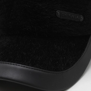 Detailed view of winter hat featuring plush faux fur texture and faux leather brim edge