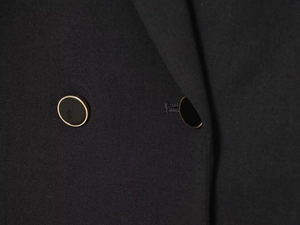 Macro shot of black fabric texture with elegant black and gold buttons on a blazer dress