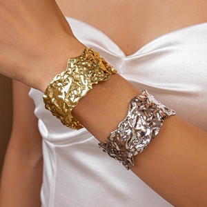 Close-up of hammered texture gold and silver metallic open cuffs on model wrist