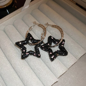 Détail de boucles d'oreilles étoiles argentées avec strass en cristal noir et rose
