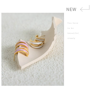 Close-up of dual-layer enamel earrings in white and lavender with gold-plated edges