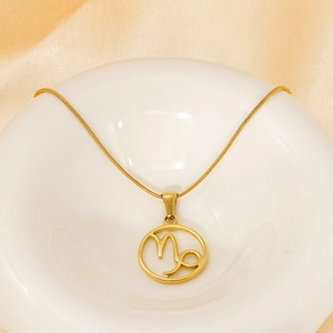 Elegant gold Capricorn zodiac necklace with hollow circular pendant on white porcelain