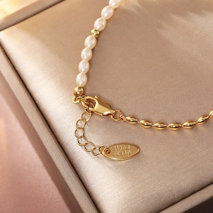 Macro shot of pearl bracelet with gold lobster clasp and Hand Made metal tag