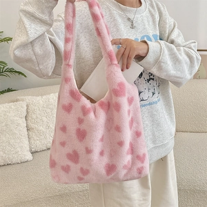 Detail of soft pink plush tote bag with heart pattern on a cozy beige sofa background