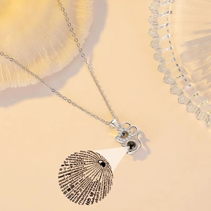 Detailed view of silver mouse projection necklace with zircons and 100 languages stone