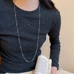 Detail of silver long layered tassel necklace with bead accents on grey knitwear
