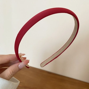 Detail view of a slim red fabric headband with non-slip lining and matte texture