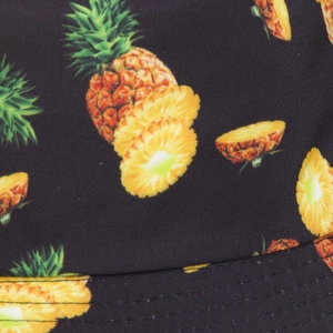 Close-up of black bucket hat featuring vivid yellow pineapple print and canvas texture