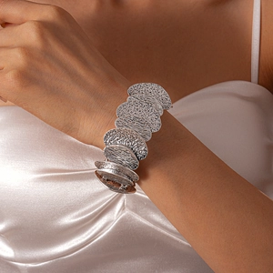 Close-up of a silver wide cuff bracelet with hammered texture on a female model