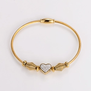 Detailed macro of gold heart charm with pavé diamonds on cable wire bracelet band
