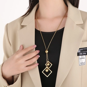 Elegant gold titanium necklace featuring cube and sphere pendants worn by a model