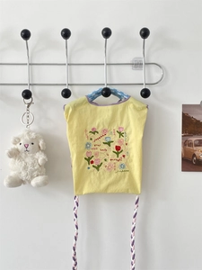 Vue détaillée du sac en coton jaune avec broderie florale et finitions violettes