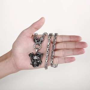 Dettaglio della catena bizantina argentata con pendente a teschio punk vintage sulla mano