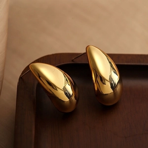Detailed macro shot of golden teardrop earrings resting on a wooden display tray