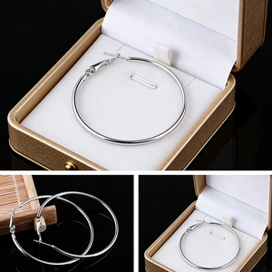 Macro detail of large polished silver hoop earrings presented in a luxury gift box