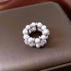 Macro shot of double-layered pearl ring with floral crystal accents on luxury brown silk