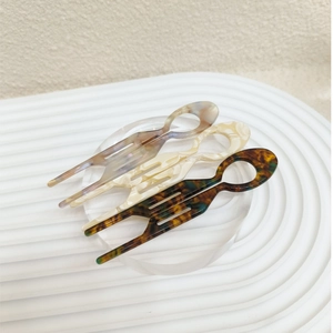 Detail of tortoise and marble acetate U-shape hair pins on minimalist wavy background