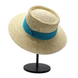 Detail of light beige boater hat showing fine straw weave and wide cyan ribbon