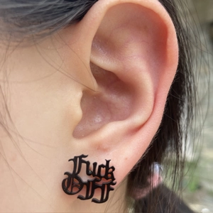 Punk style black letter earrings with Fuck Off cut-out design on a female model