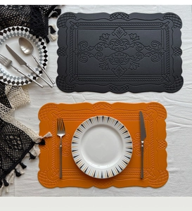 Detail of embossed faux leather placemats with scalloped edges in black and orange