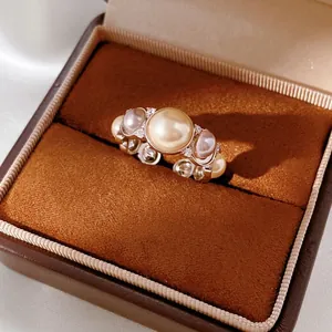 Vintage style gold ring with central gold pearl and zircon accents in a leather jewelry box