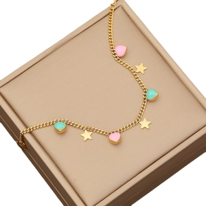 Golden chain bracelet with star charms and pink blue enamel hearts on jewelry box