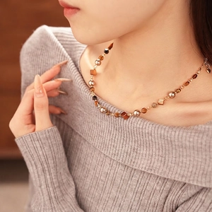 Tiger eye beaded necklace with heart pendant on gray sweater for vintage style