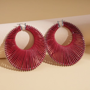 Close-up of red woven texture on silver hoop earrings with a bohemian geometric design