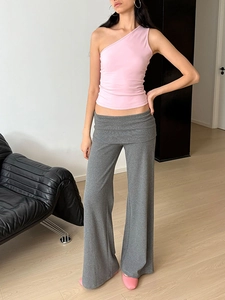 Détail du haut en coton rose à une épaule et du pantalon large en tricot gris
