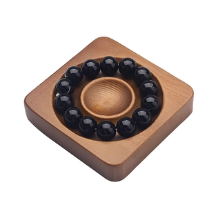 Polished black bead bracelet on minimalist square wooden display tray on white background