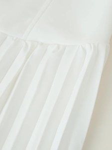 Nahaufnahme eines weißen Plisseekleid-Saums mit eleganter Textur und feinen Nähten