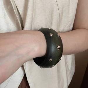 Vue détaillée du bracelet en bois sombre avec des clous argentés en forme d'étoile et ronds