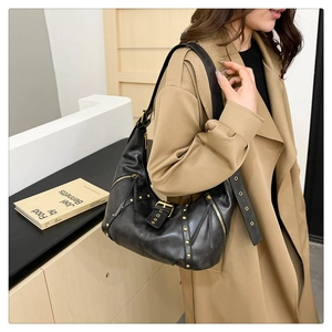 Detailed view of black leather hobo bag with gold zippers and rivet trim on model