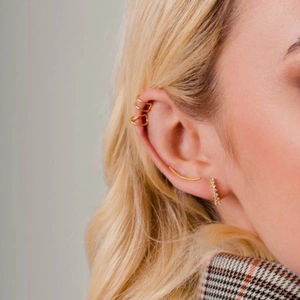 Detail of gold hoop earrings set with colorful zircon and geometric ear cuffs on model