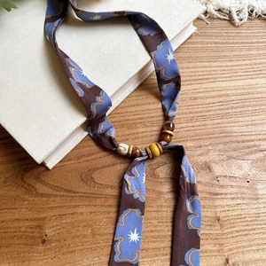 Detailed close-up of a printed chiffon necklace featuring wood beads and star motifs