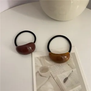 Detailed shot of resin hair ties in dark brown and amber colors on a minimalist desk