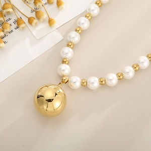 Close-up of pearl necklace with gold beads and a large mirror-finish golden sphere pendant
