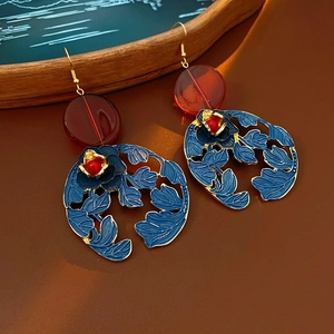Detailed view of vintage gold earrings with blue enamel flowers and deep red beads