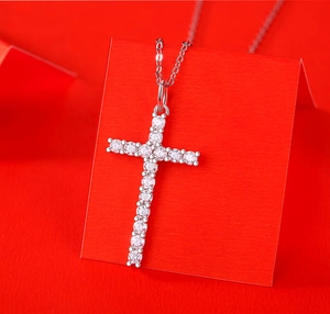 Macro shot of 925 silver cross pendant with pavé moissanite on red background