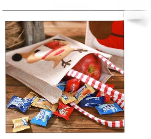 Detail of burlap Christmas gift bag with reindeer patch, holding an apple and candies