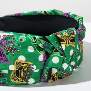 Detail of green carnival headband with Venetian mask print and stylish top knot design