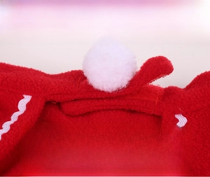 Detail showing red fleece fabric with white pom-pom and adjustable velcro closure