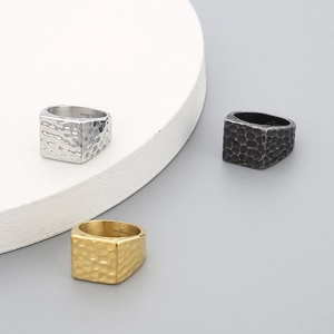Macro detail of hammered texture and 316L stamp on gold, silver, and black square rings