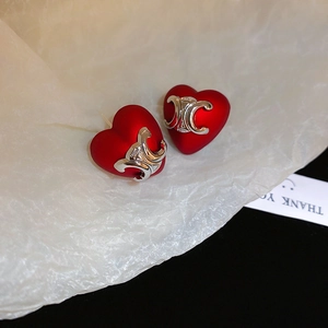 Close-up of red heart earrings with matte finish and silver metal logo detail