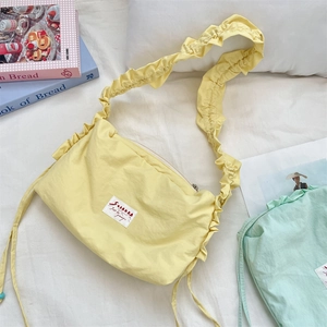Detail showing lemon yellow pleated ruffled shoulder bag with brand label on fabric